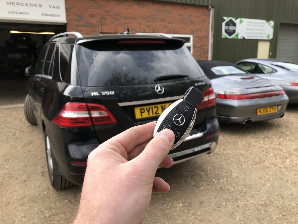 Mercedes key held in front of a black Mercedes