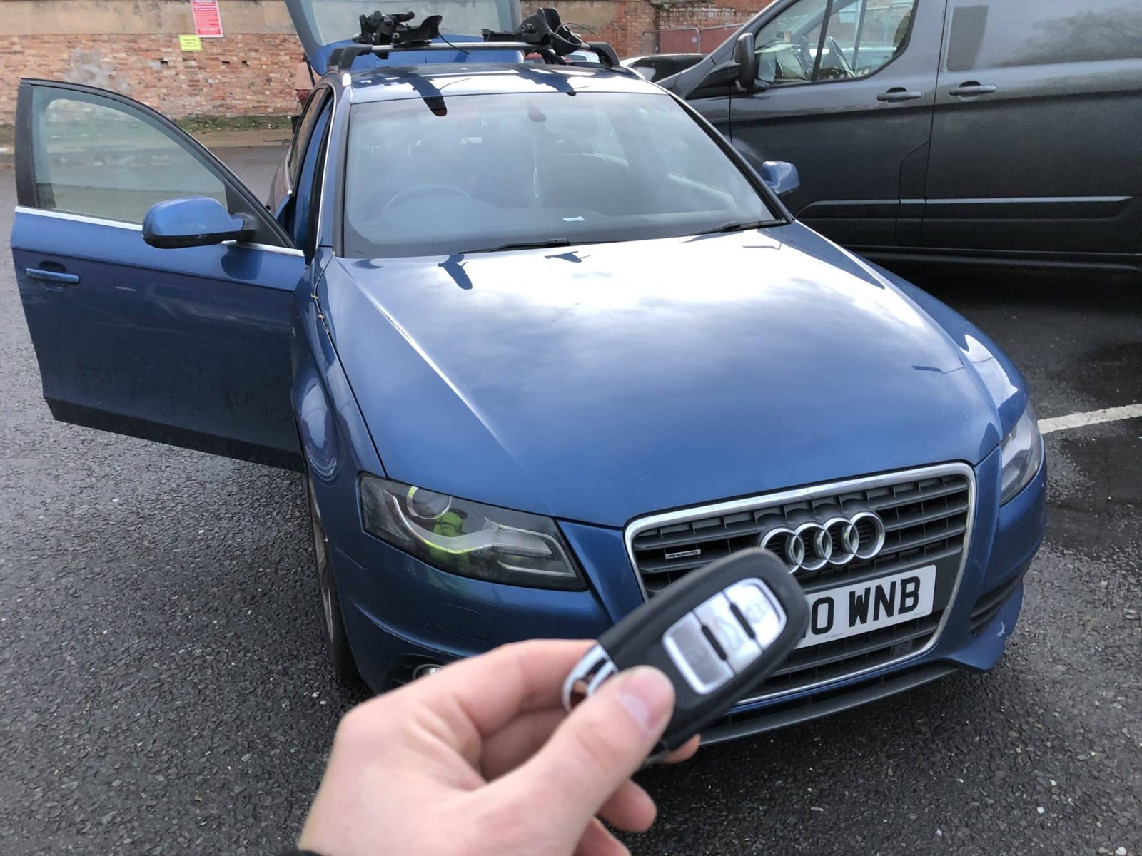 Audi remote key held in front of a blue Audi